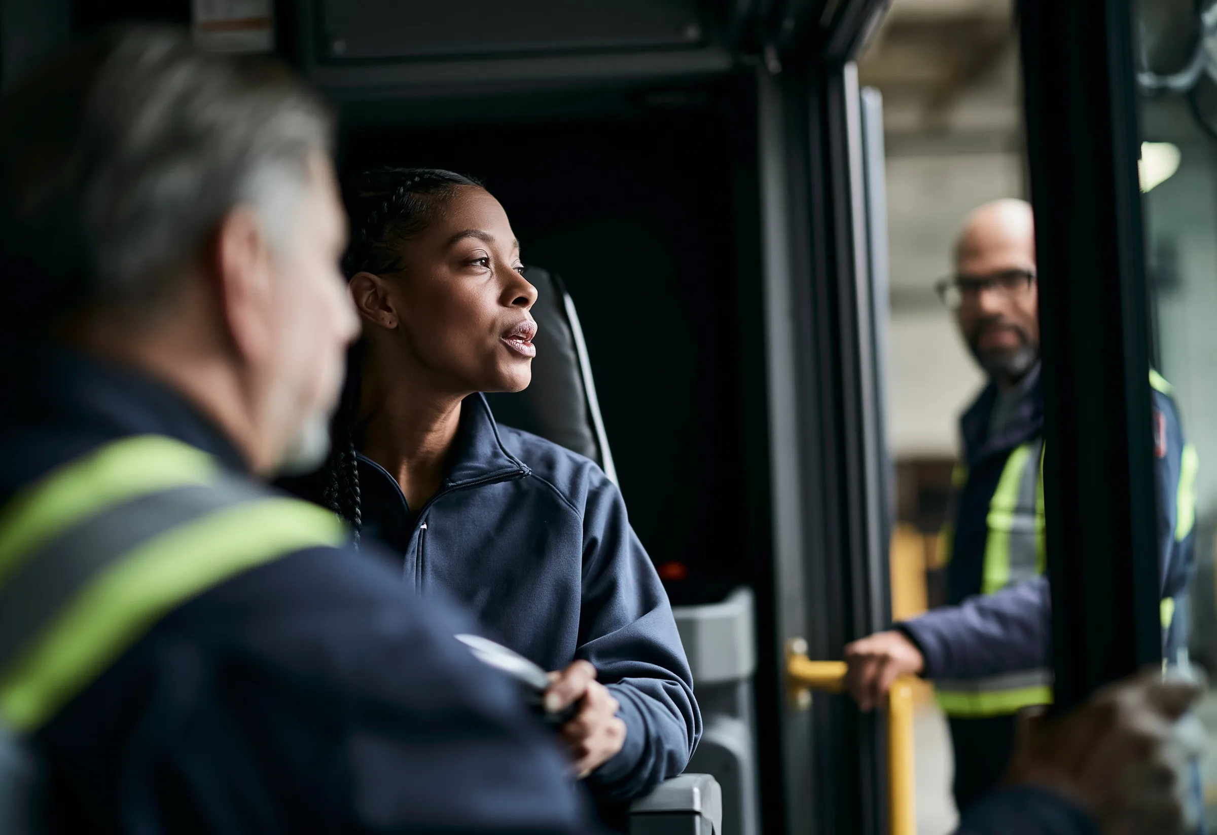 Transit colleagues talking at the open door of a bus in the garage
