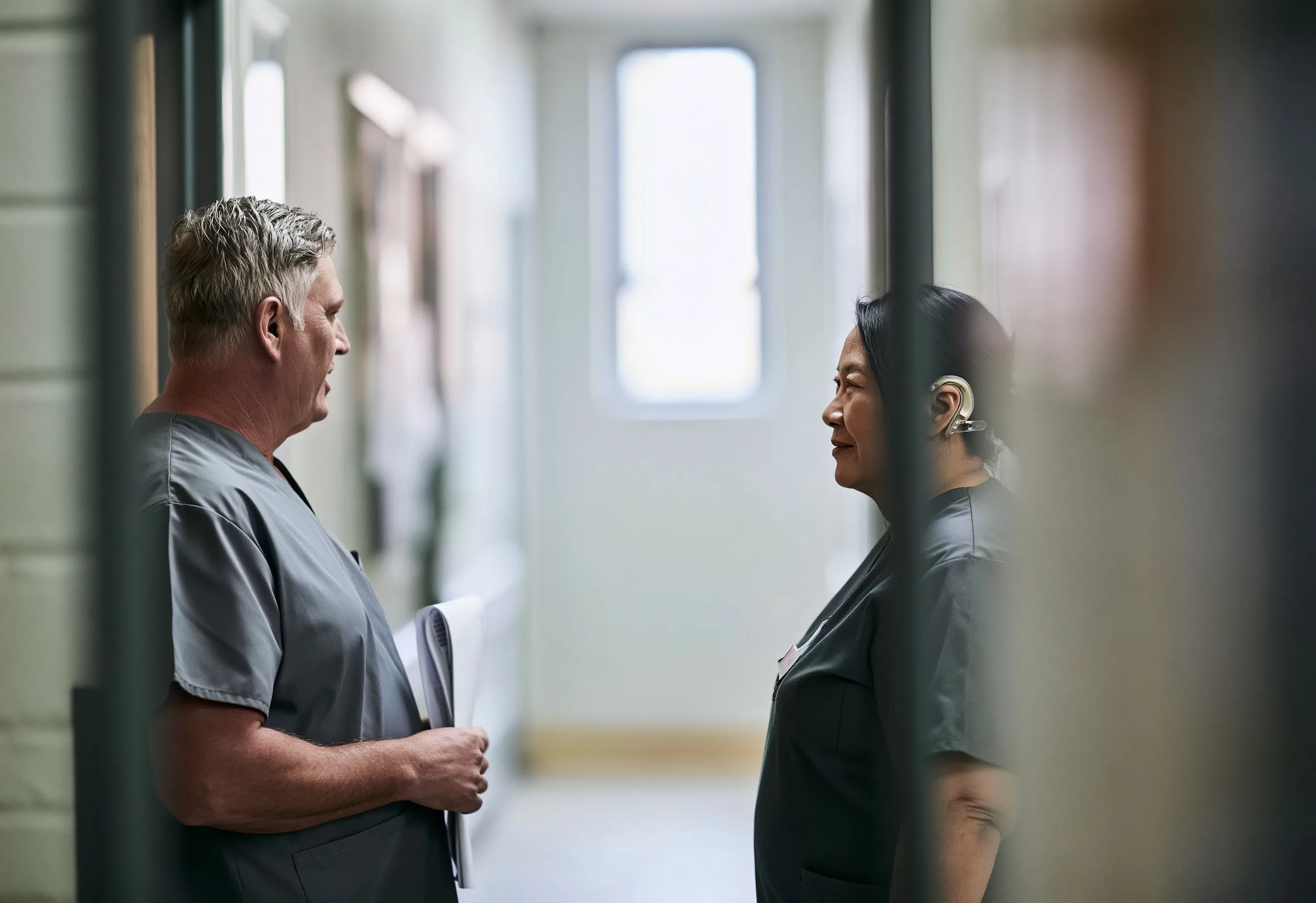 Two hospital staff in scrubs talking in a bright corridor